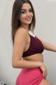 A woman in a maroon top and pink skirt posing for a picture.