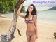 A woman in a bikini standing on a beach.