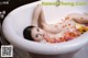 A naked woman laying in a bathtub filled with flowers.