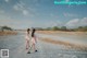 A couple of women walking down a dirt road.