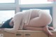 A woman laying on top of a kitchen counter next to a window.