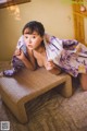 A woman in a purple and white kimono laying on a bed.