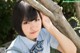 A young woman in a school uniform leaning against a tree.