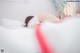 A woman laying on a bed in a white and red lingerie.