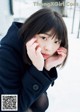 A woman in a black coat is sitting in the snow.