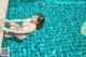 A woman in a white bathing suit is floating in a pool.