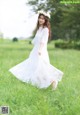 A woman in a white dress walking through a field.